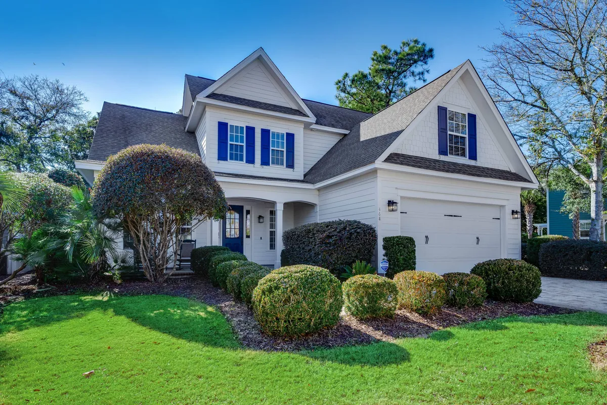 Featuring a charming front porch framed by a landscaped garden and a garage door, this exterior shot showcases the welcoming entryway of the home. The inviting atmosphere hints at outdoor living, relaxation, and the convenience of garage access for storing golf gear.